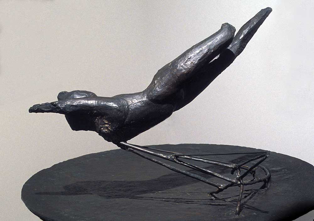 Sculpture. A bronze object like a diving bird or falling person is supported by a cantilevered wire base.